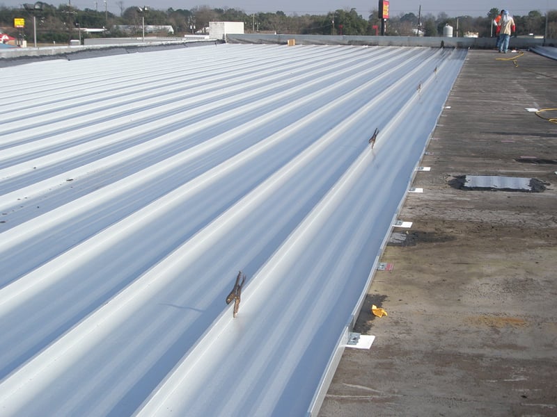 Low-slope metal roof recover system installed over an existing roof